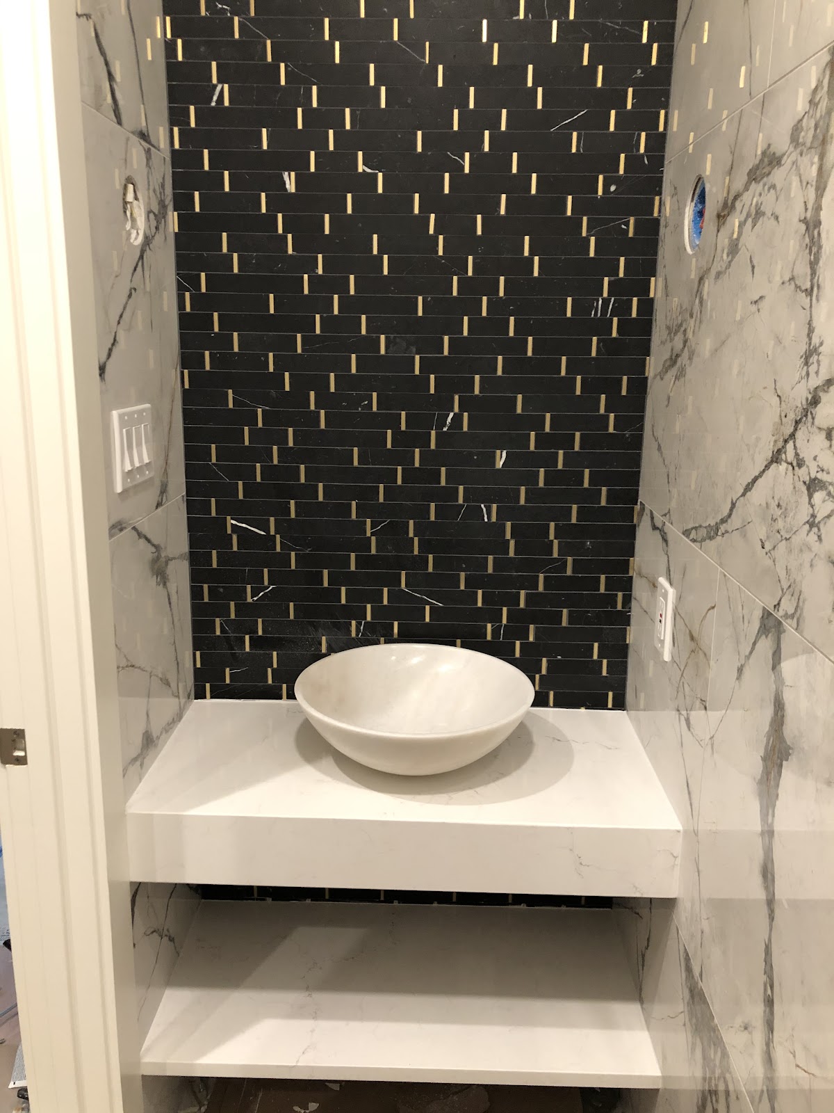 Powder room vessel sink with marble and black mosaic tile